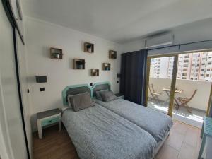 a bedroom with a bed and a large window at Santos LODGE surf - 5 minutes walking to Praia da Rocha in Portimão