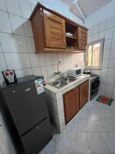 a small kitchen with a sink and a refrigerator at Résidence Allégra in Yaoundé