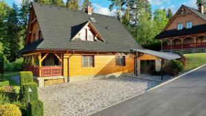 a large wooden house with a driveway in front of it at Chata Anna s privátnym wellness in Námestovo