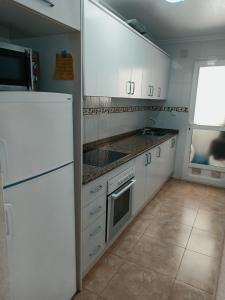 Formentera de SeguraにあるApartamento Formenteraの白いキャビネット、シンク、冷蔵庫付きのキッチンが備わります。