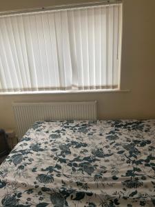 a bedroom with a bed with a floral bedspread and a window at 8 Challanor road in Yarm