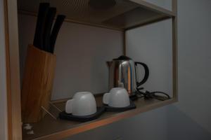 a tea kettle and two mugs on a shelf at Delfino in Pietrapertosa