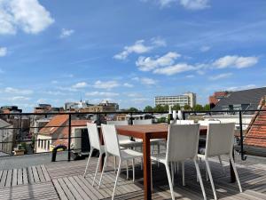 a wooden table and white chairs on a roof at Antwerpcityhome in Antwerp