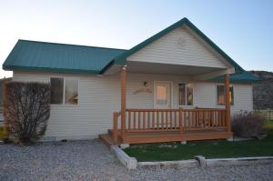 a small white house with a porch with a green roof at Sleepy J Cabins in Swan Valley