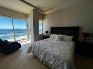 a bedroom with a bed with a view of the ocean at ACCESS - BEACH Penthouse PAPAS and BEER 2 miles WIFI in Rosarito