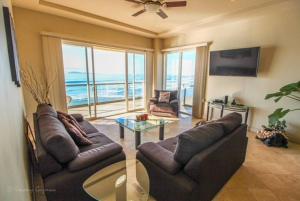 a living room with two couches and a glass table at ACCESS - BEACH Penthouse PAPAS and BEER 2 miles WIFI in Rosarito