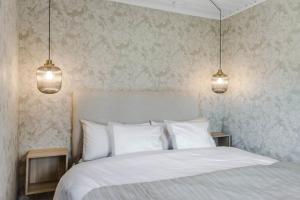 a bedroom with a white bed with two pendant lights at Nyrenoverat gårdshus på havstomt med hög standard in Örnsköldsvik