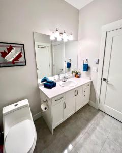 a bathroom with a sink and a toilet and a mirror at Kelowna new lake view 2bedrooms suite close BIG WHITE in Kelowna