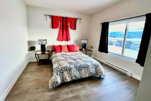 Un dormitorio con una cama con almohadas rojas y una ventana en Kelowna new lake view 2bedrooms suite close BIG WHITE, en Kelowna