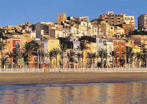 a group of buildings and palm trees on the beach at La Voreta in Villajoyosa