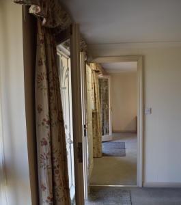 a hallway with curtains and a door with a mirror at Sandhurst Farm Forge Self Catering Stableblock in Sittingbourne