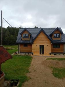 uma casa de madeira com um telhado preto em Agroturystka Podlasie Dom całoroczny nad stawem em Dobrzyniewo Duże