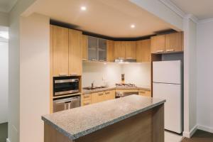 a kitchen with wooden cabinets and a white refrigerator at Newcastle Central Plaza Apartment Hotel Official in Newcastle