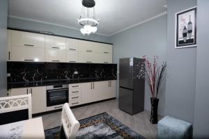 a kitchen with white cabinets and a black refrigerator at Elton's Home in Pogradec