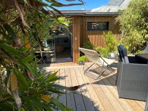 una terraza de madera con sillas y una casa en Lodge LE CABANON accès direct plage !, en La Turballe