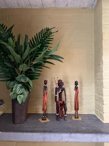 trois figurines assises sur une étagère à côté d'une plante en pot dans l'établissement De Wabisabiboerderij, à Oedelem