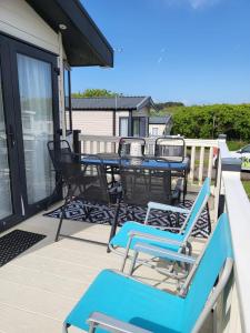 een patio met blauwe stoelen en een tafel op een veranda bij Luxury Woodland Retreat Holiday Home - Shorefield Country Park in Downton