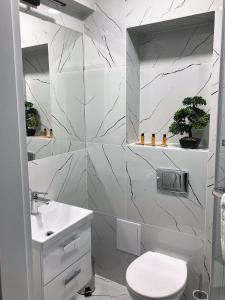 a white bathroom with a toilet and a sink at Apartamenty Planeta Mielno in Mielno +44 photos