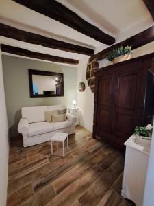 een woonkamer met een witte bank en houten vloeren bij Il Gelsomino Apartment in Pitigliano