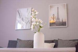 a white vase with flowers in it on a table at "Purple Chill" Super Zentrale Ferienwohnung HBF-Messe-Buergerweide-CityGate-OVB Arena in Bremen