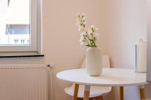 un jarrón blanco con flores blancas sentado en una mesa en "Purple Chill" Super Zentrale Ferienwohnung HBF-Messe-Buergerweide-CityGate-OVB Arena en Bremen