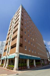 a large brown building with white columns on a street at Dukes Hotel Nakasu in Fukuoka