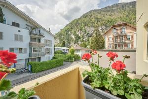 Stay Switzerland Apartments في إنترلاكن: شرفة مع الزهور الحمراء على مبنى