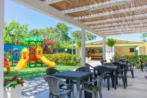 eine Terrasse mit Tischen und Stühlen sowie einem Spielplatz in der Unterkunft Camping Parco Vacanza Partaccia 2 in Marina di Massa
