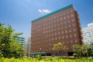 a tall brown building with a green roof at Dukes Hotel Nakasu in Fukuoka
