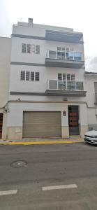 Edificio blanco con 2 puertas de garaje y balcón en CASUAL SUITES GANDIA CENTRO, en Gandía