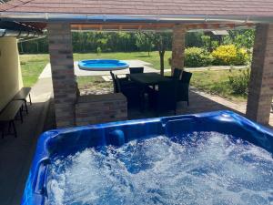una gran bañera de hidromasaje azul en un patio con mesa en Levendulás Tanya Szarvas - Jakuzzi és medence, en Szarvas