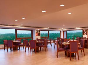a dining room with tables and chairs and large windows at Lemon Tree Hotel, Dehradun in Dehradun