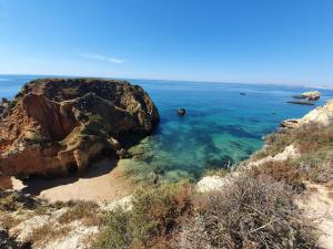 a beach with rocks and the blue water at Santos LODGE surf - 5 minutes walking to Praia da Rocha in Portimão