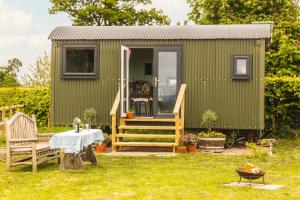 a green tiny house in a yard with a table at Mulsford Cottage in Malpas