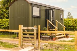 a green tiny house with a wooden fence at Mulsford Cottage in Malpas
