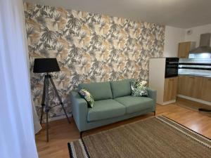 uma sala de estar com um sofá verde em frente a uma parede em Le cosy em Courseulles-sur-Mer