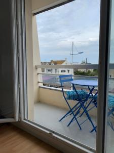 una mesa y una silla en un balcón con vistas en Le cosy en Courseulles-sur-Mer