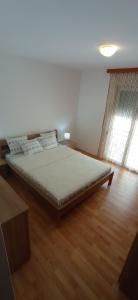 een groot bed in een kamer met een houten vloer bij Apartman S Igalo in Herceg-Novi