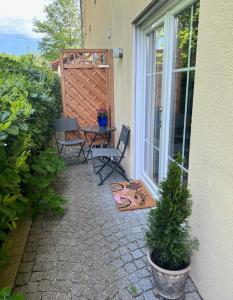 eine Terrasse mit 2 Stühlen und einem Tisch neben einem Fenster in der Unterkunft Ferienwohnung Mazur in Murnau am Staffelsee
