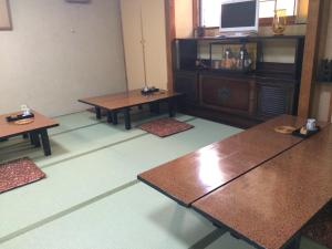 a room with tables and a tv on a wall at Nihonkan in Kyoto