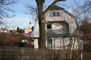 una casa blanca detrás de una valla con un árbol en Ferienwohnung Mazur, en Murnau am Staffelsee