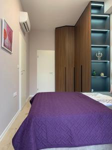 a bedroom with a purple bed and a wooden cabinet at Lovely 1-bedroom Condo in Tirana WiFi-Netflix-AC in Tirana