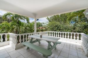 a white porch with a picnic table on a white balcony at The Green Turtle Eco Lodge in Willemstad