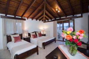 a bedroom with two beds and a vase of flowers at Afrodite Hotel Apartments in Myrina