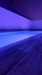 een leeg zwembad in een kamer met paarse verlichting bij Escapada Delux in Ossa de Montiel
