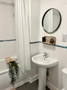 Baño blanco con lavabo y espejo en 2 Bedroom Serviced Apartment with Free Parking, Wifi & Netflix, Basingstoke en Basingstoke