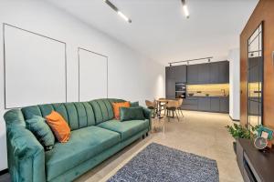 a living room with a green couch and a kitchen at Luxury Copper Apartment in Łódź