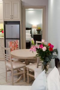 a dining room table and chairs with a vase of pink flowers at Afrodite Hotel Apartments in Myrina