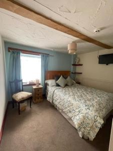 1 dormitorio con 1 cama, 1 silla y 1 ventana en The Crosskeys Inn, en Usk