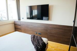 a bedroom with a bed and a flat screen tv at The Apartment - Luxury Stay Budva in Budva